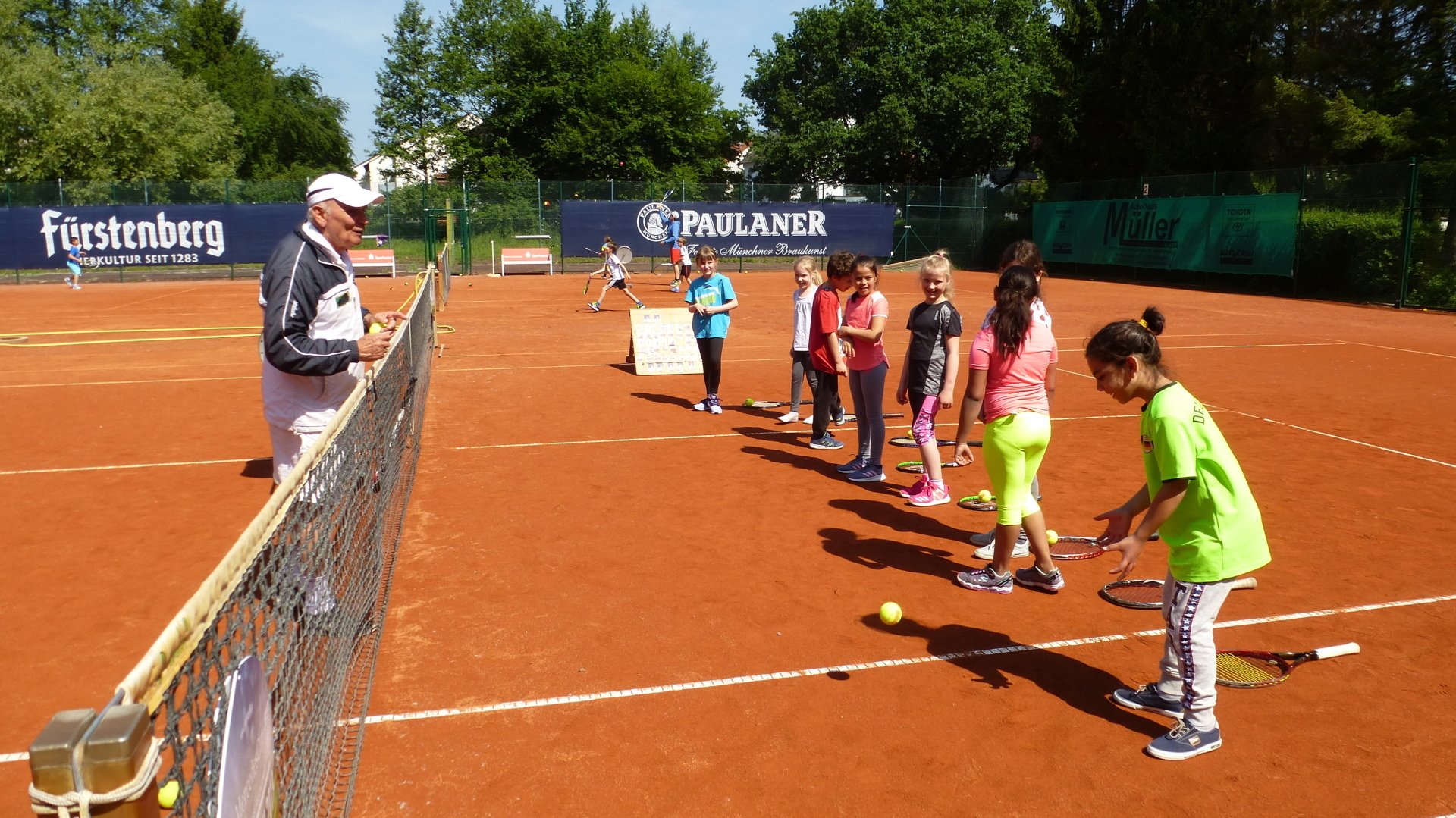 Schüler mit Trainern auf dem Tennisplatz